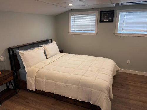 a bedroom with a bed with white sheets and two windows at Private Penthouse Studio in Providence