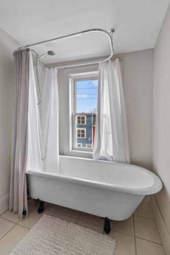a white bath tub in a bathroom with a window at Historic Jelly Bean Row House Walk to Signal Hill in St. John's