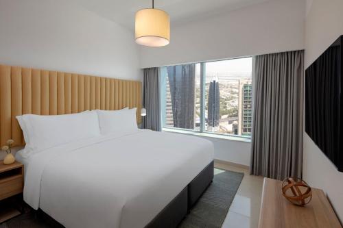 a bedroom with a large bed and a large window at Staybridge Suites Dubai Financial Centre by IHG in Dubai