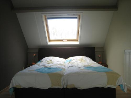 a bedroom with a bed with a window above it at Stylish Holiday Home in Zuidzande with Sauna in Zuidzande