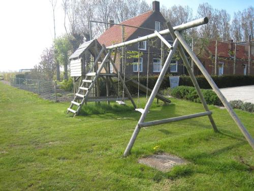 a swing set in the grass in front of a house at Stylish Holiday Home in Zuidzande with Sauna in Zuidzande