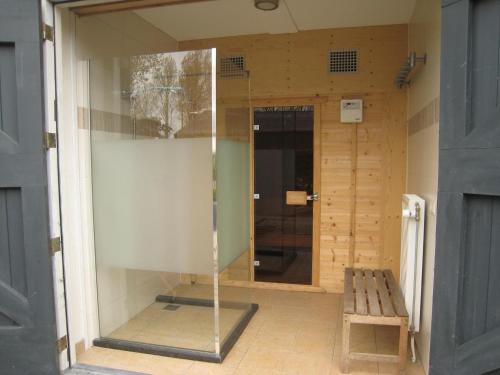 a glass shower in a room with a bench at Stylish Holiday Home in Zuidzande with Sauna in Zuidzande