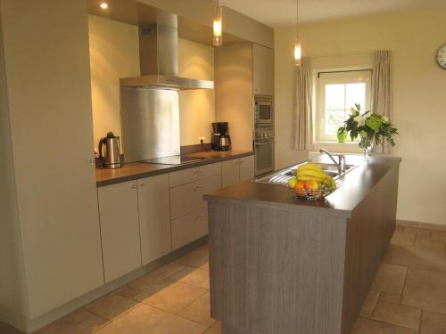a kitchen with a sink and a bowl of fruit on a counter at Stylish Holiday Home in Zuidzande with Sauna in Zuidzande