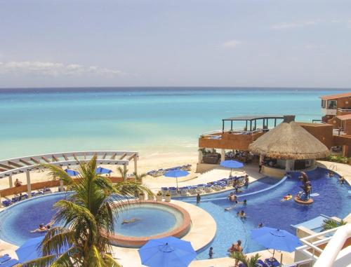 a resort with two pools with blue umbrellas and the ocean at SUNSET FISHERMEN BEACH & SPA RESORT-Optional All Inclusive- 3 UNITS CHOICE-ROOM - 344A Ocean view with terrace- ROOM 344B No terrace, View from window to park - STUDIO 344C Ocean View Studio for 2- Playacar Beach, Phase 1-NO ELEVATOR! in Playa del Carmen