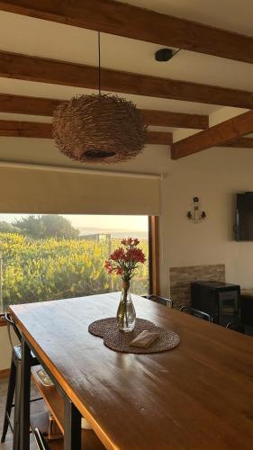 a dining room table with a vase of flowers on it at Casa Olas, Refugio Costero in Curanipe
