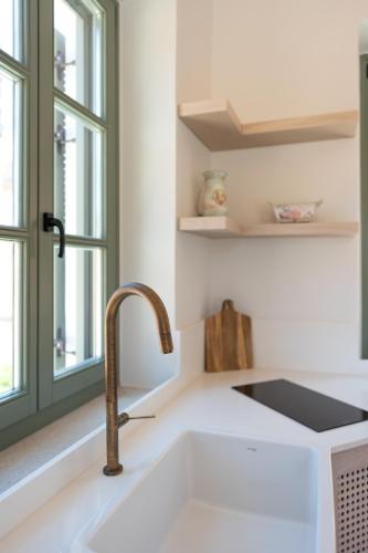a white kitchen with a sink and a window at Nisomar Suites in Symi