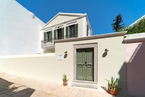 a white house with a green door at Nisomar Suites in Symi