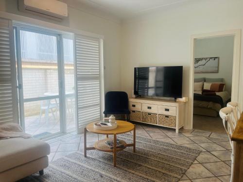 una sala de estar con un televisor y una mesa en Bahia by the Beach, en Avoca Beach