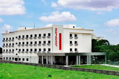 a white building with a red sign on it at Ginger Tirupur in Tiruppūr