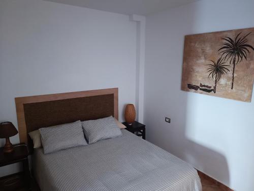 Un dormitorio con una cama y un cuadro en la pared. en Casa de Famara, en Famara