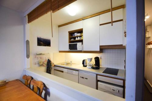 une petite cuisine avec des armoires blanches et une table dans l'établissement Résidence Aime 2000 - 4 Pièces 7/8 pers - AIME 2000 - PLAGNE AIME 2000- WIFI MAE-1864, à La Plagne Tarentaise