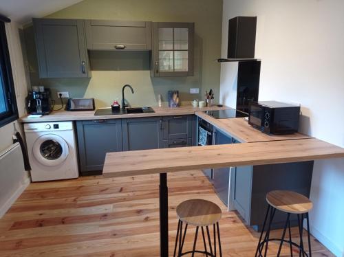 une cuisine avec un comptoir en bois et deux tabourets dans l'établissement La grange, entre Pyrénées et Andes, à Seich