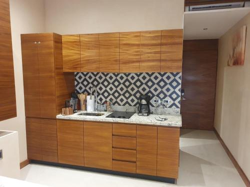 a kitchen with wooden cabinets and a counter top at SOLEMN Cabañas Villaseñor in Tulum