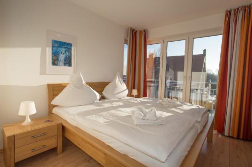 een slaapkamer met een bed met witte lakens en een raam bij Ferienwohnung Wiek im Hafenkieker in Wiek auf Rügen 