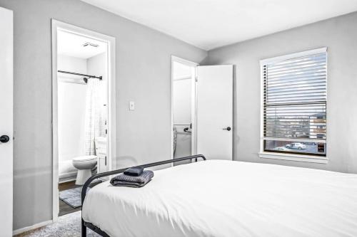 a white bedroom with a bed and a bathroom at Embrace Austins Vibrant Heart Elegant 1BR Haven in Austin