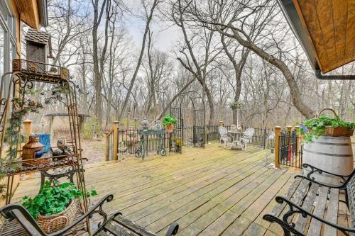a wooden deck with chairs and a table and trees at Walk to Saylorville Lake Spacious Home with Deck! in Johnston