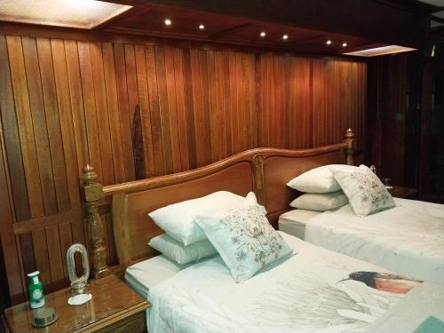 two beds in a room with wooden walls at De La Grace in Potchefstroom