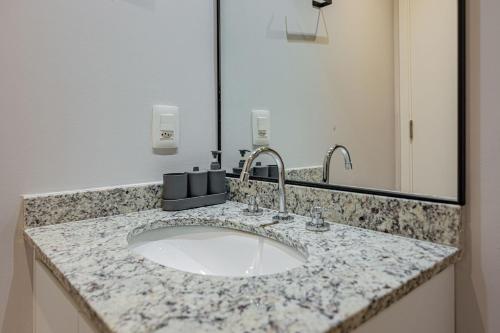 a bathroom counter with a sink and a mirror at Piscina no Rooftop! Studio a 3min do Metrô República in Sao Paulo