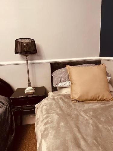 a bedroom with a bed and a lamp on a table at Spacious 5 Bedroom Home in Central Kidderminster with Private Parking and Electric Vehicle Facilities, Easy Access to Birmingham and Nearby Towns in Kidderminster