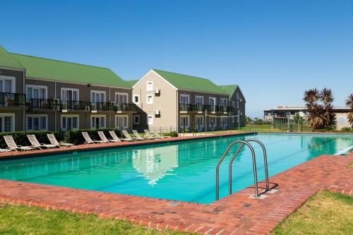 a large swimming pool with chairs and buildings at Protea Hotel by Marriott Stellenbosch & Conference Centre in Stellenbosch