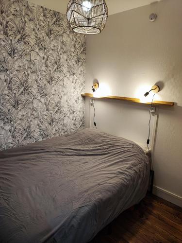 - une chambre avec un lit et deux lampes murales dans l'établissement Cocon paisible en centre ville, à Luchon