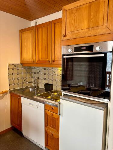 une cuisine avec des armoires en bois et un four à plaques de cuisson dans l'établissement Appartement 4 personnes - Magnifique vue montagne, à Méribel