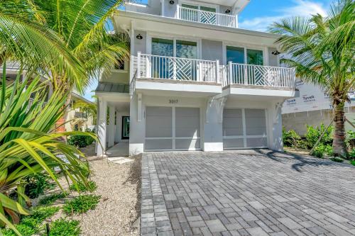 a large white house with palm trees and a driveway at Coming In Hot in Holmes Beach