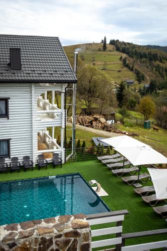 a house with a swimming pool with chairs and umbrellas at Villa Olexandr&Matvii in Bukovel