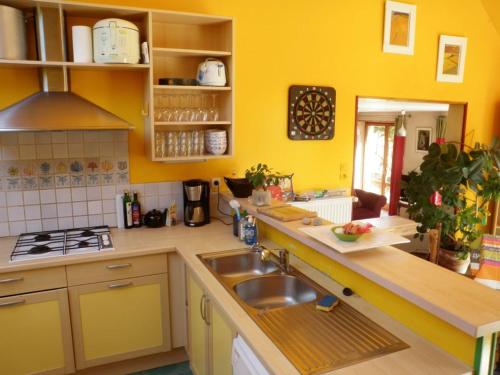 une cuisine jaune avec évier et cuisinière dans l'établissement La Maison De Balou, à Pleumeur-Bodou