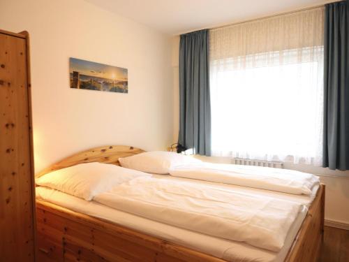 ein Schlafzimmer mit einem Holzbett mit Fenster in der Unterkunft Freundliches 2-Zimmer-Appartement mit Kieferneinrichtung und einem Balkon. in Westerland