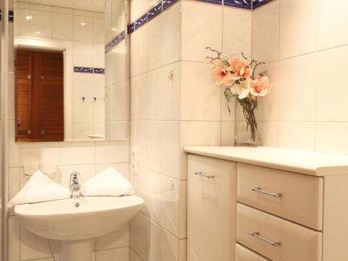 ein weißes Badezimmer mit einem Waschbecken und einer Vase aus Blumen in der Unterkunft Freundliches 2-Zimmer-Appartement mit Kieferneinrichtung und einem Balkon. in Westerland