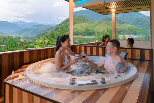 a man and woman sitting in a bath tub with glasses of wine at Mercedes Lodge in San Ramón