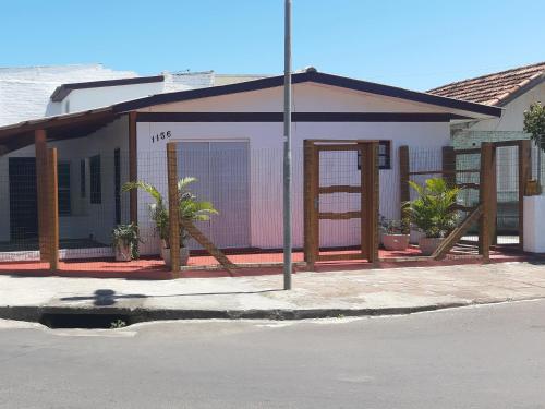 a small building with wooden posts on the side of a street at Casa no Centro - Perto do mar e do rio in Tramandaí
