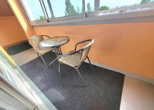 - deux chaises et une table dans une chambre avec fenêtre dans l'établissement Studio Opale proche Bâle, gare et aéroport, à Saint-Louis