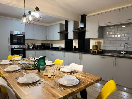 a kitchen with a wooden table with plates and wine glasses at Large House for 21 - Nottingham City in Nottingham