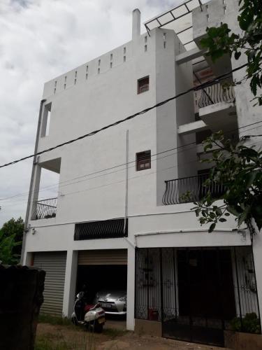 a white building with a car parked in front of it at Beverly Edge Villa in Sri Jayewardenepura Kotte