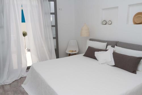 a white bedroom with a large white bed with pillows at Apartments Enosis, Alia in Agios Prokopios