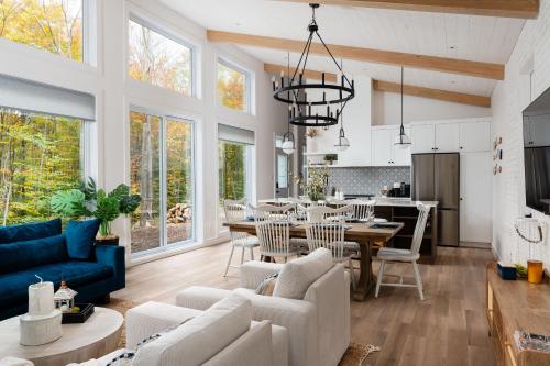 a living room with white furniture and a dining room at Chalet Eau, style Lake house à Tremblant in Lac-Superieur