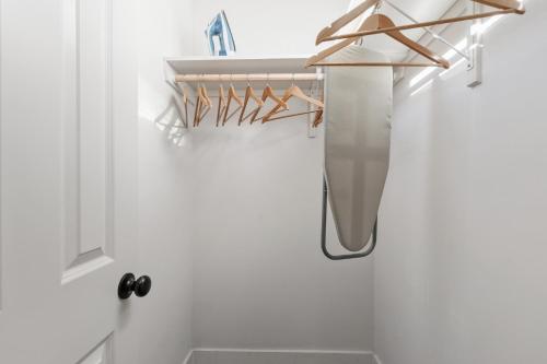 ein Bad mit einer weißen Wand und einem Schrank mit Kleiderbügeln in der Unterkunft Bourbon House King Bed Luxury Amenities Fast WiFi in Lafayette