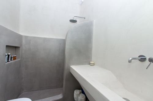 a white bathroom with a sink and a tub at Apartments Enosis, Alia in Agios Prokopios
