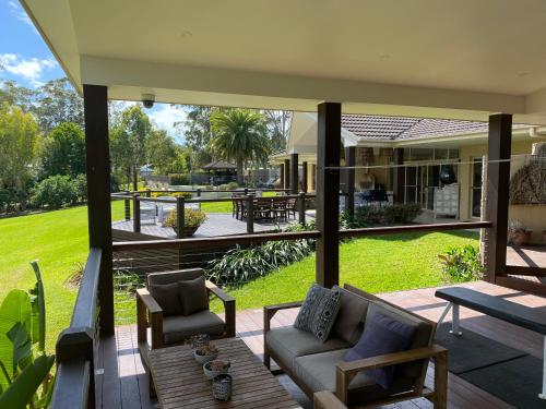 a patio with a couch and chairs on a porch at Emerald Beach Lakefront Luxury Mansion in Emerald Beach