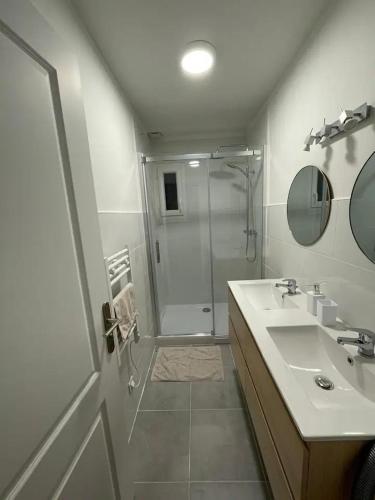 une salle de bain blanche avec une douche et un lavabo dans l'établissement Maison familiale proche Paris, à Domont