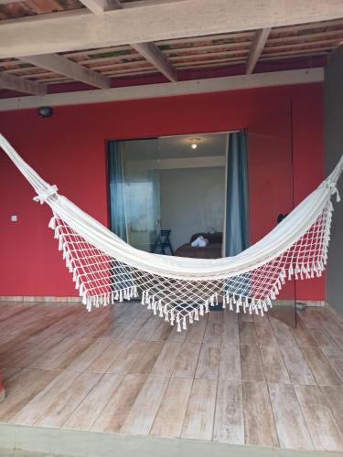 a hammock in a room with a red wall at Vila Penelope Guest House in Balneário Camboriú