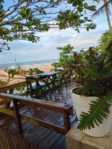 a wooden deck with a table and benches on the beach at Vila Penelope Guest House in Balneário Camboriú