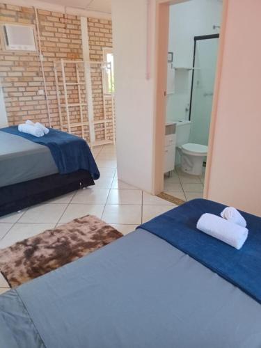 a bedroom with two beds and a bathroom with a mirror at Vila Penelope Guest House in Balneário Camboriú