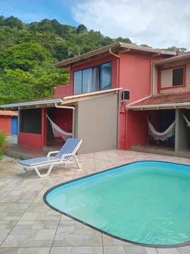 a house with a swimming pool and a chair and a house at Vila Penelope Guest House in Balneário Camboriú