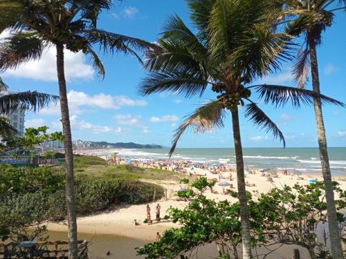 a beach with palm trees and a crowd of people at Vila Penelope Guest House in Balneário Camboriú