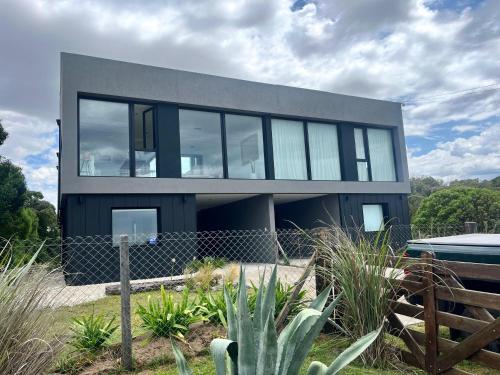 a black house with glass windows and a fence at Casa en chapa vista al mar Zona Cruz del Sur - Altamar - Hola Sur in Chapadmalal