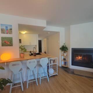 a kitchen with a bar with stools and a fireplace at Warm & cozy loft full of light, Ski-in Ski-out in Stoneham