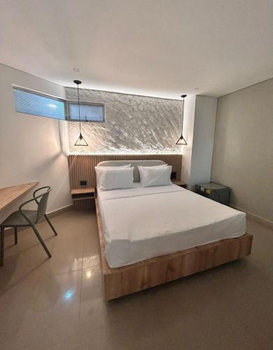 a bedroom with a bed and a desk and a window at Hotel Time Oclock in Medellín